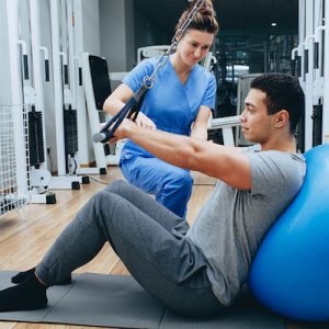 kinesiologist helps a mixed race man doing exercises to strengthen his back muscles. treatment of back pain using kinesitherapy. (kinesiologist helps a mixed race man doing exercises to strengthen his back muscles. treatment of back pain using kinesit