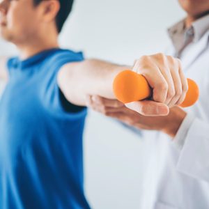 Physiotherapist man giving exercise with dumbbell treatment About Arm and Shoulder of athlete male patient Physical therapy concept